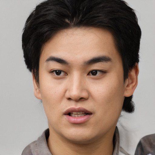 Joyful asian young-adult male with short  black hair and brown eyes