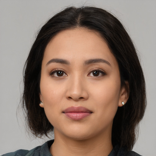 Joyful latino young-adult female with medium  brown hair and brown eyes