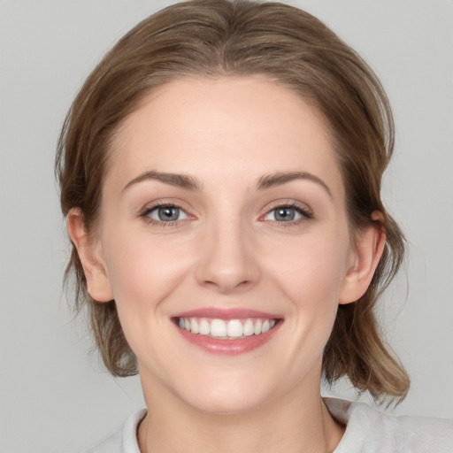 Joyful white young-adult female with medium  brown hair and grey eyes