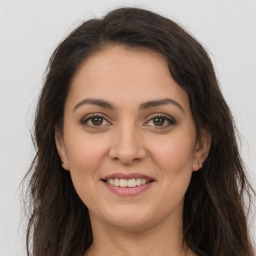 Joyful white young-adult female with long  brown hair and brown eyes