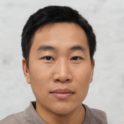Joyful asian young-adult male with short  black hair and brown eyes