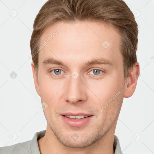 Joyful white young-adult male with short  brown hair and grey eyes