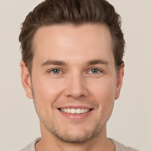 Joyful white young-adult male with short  brown hair and grey eyes