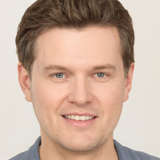 Joyful white young-adult male with short  brown hair and grey eyes