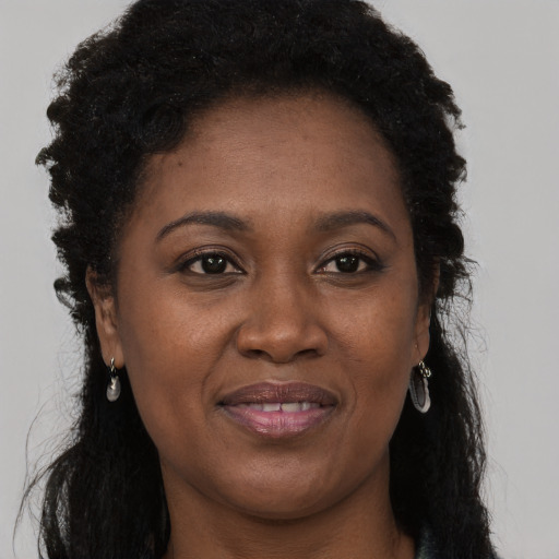 Joyful black young-adult female with long  brown hair and brown eyes