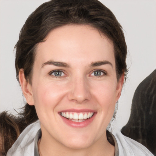 Joyful white young-adult female with medium  brown hair and grey eyes