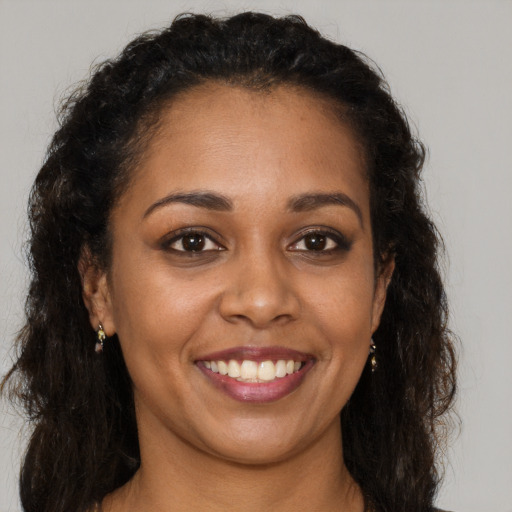Joyful black young-adult female with long  brown hair and brown eyes