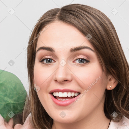 Joyful white young-adult female with medium  brown hair and green eyes