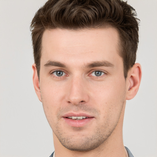 Joyful white young-adult male with short  brown hair and grey eyes