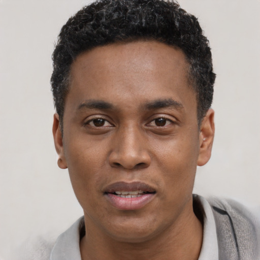 Joyful black young-adult male with short  black hair and brown eyes