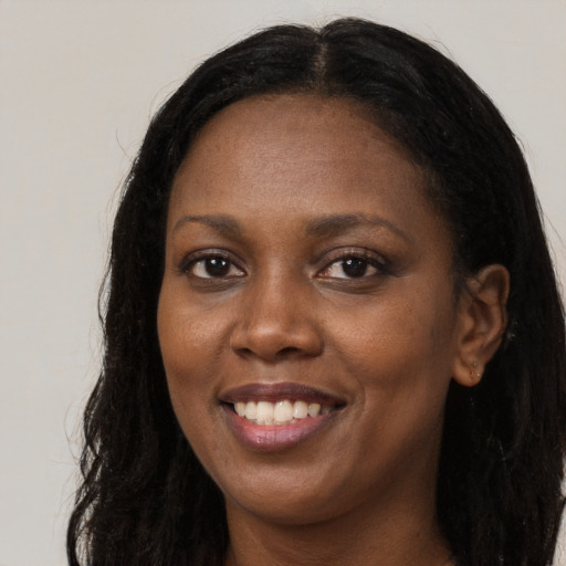 Joyful black young-adult female with long  brown hair and brown eyes