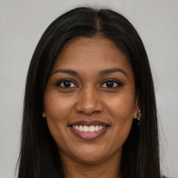 Joyful black young-adult female with long  brown hair and brown eyes