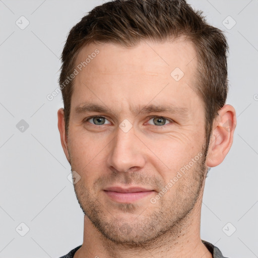 Joyful white young-adult male with short  brown hair and grey eyes