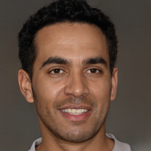 Joyful latino young-adult male with short  brown hair and brown eyes