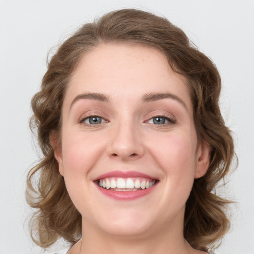 Joyful white young-adult female with medium  brown hair and blue eyes