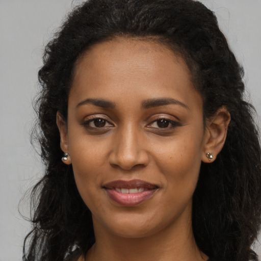 Joyful black young-adult female with long  brown hair and brown eyes