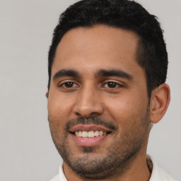 Joyful latino young-adult male with short  black hair and brown eyes