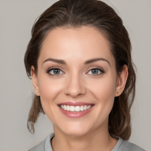 Joyful white young-adult female with medium  brown hair and grey eyes