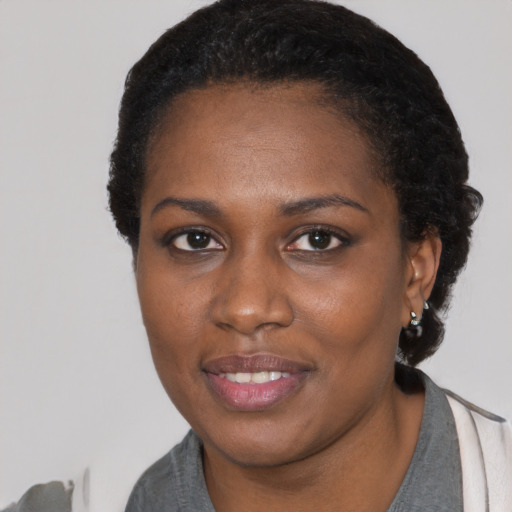 Joyful black young-adult female with short  black hair and brown eyes
