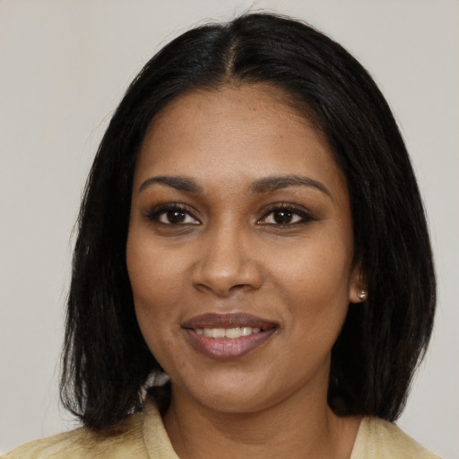 Joyful black young-adult female with long  black hair and brown eyes