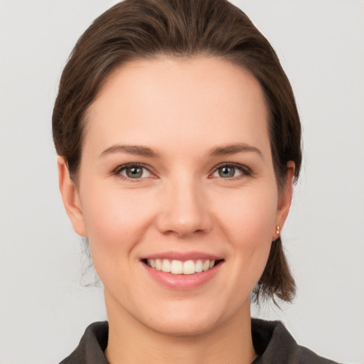 Joyful white young-adult female with medium  brown hair and grey eyes