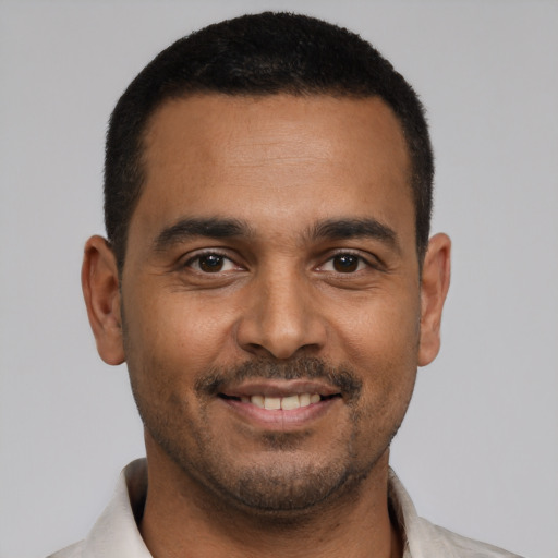 Joyful latino young-adult male with short  black hair and brown eyes
