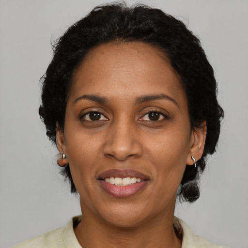 Joyful black adult female with short  black hair and brown eyes