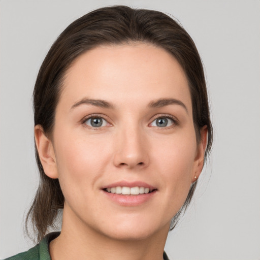 Joyful white young-adult female with medium  brown hair and grey eyes