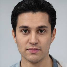 Joyful white young-adult male with short  black hair and brown eyes