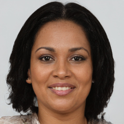 Joyful black adult female with long  brown hair and brown eyes
