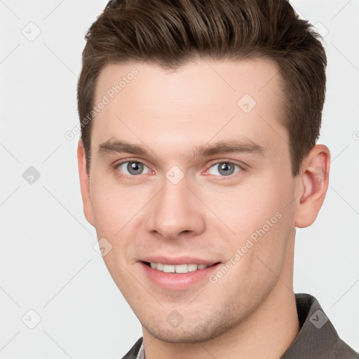 Joyful white young-adult male with short  brown hair and grey eyes