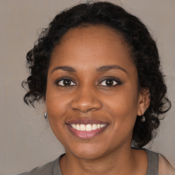 Joyful black young-adult female with long  brown hair and brown eyes