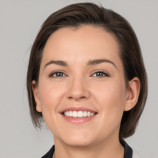 Joyful white young-adult female with medium  brown hair and grey eyes