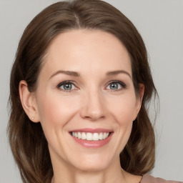 Joyful white young-adult female with medium  brown hair and grey eyes