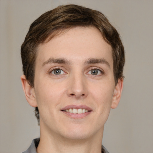 Joyful white young-adult male with short  brown hair and grey eyes