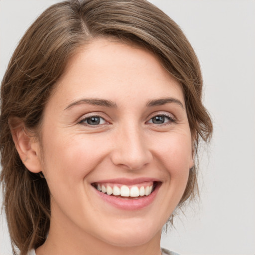 Joyful white young-adult female with medium  brown hair and grey eyes