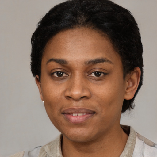 Joyful black young-adult female with short  black hair and brown eyes