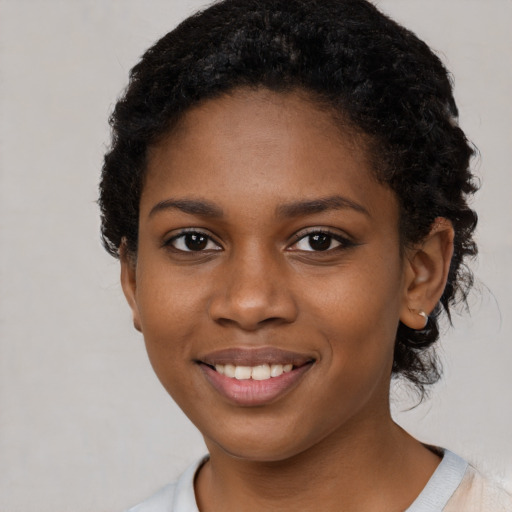 Joyful black young-adult female with short  black hair and brown eyes