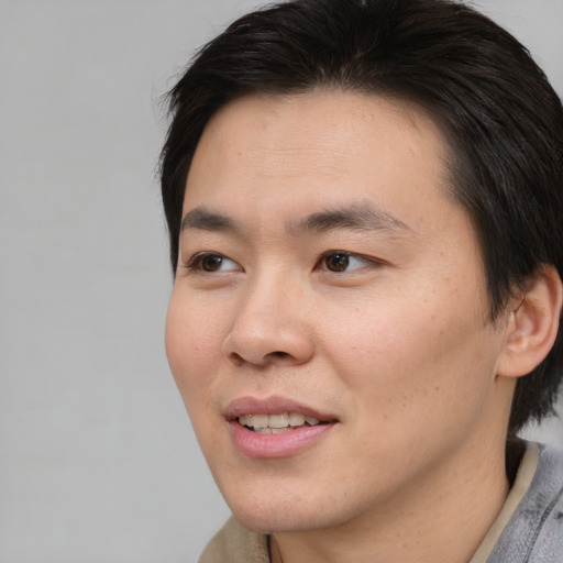 Joyful asian young-adult male with medium  brown hair and brown eyes