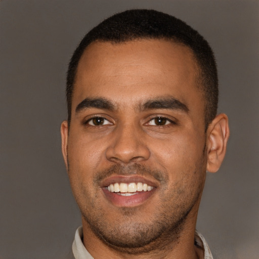 Joyful black young-adult male with short  brown hair and brown eyes