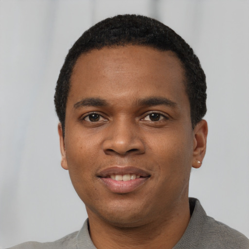 Joyful black young-adult male with short  black hair and brown eyes