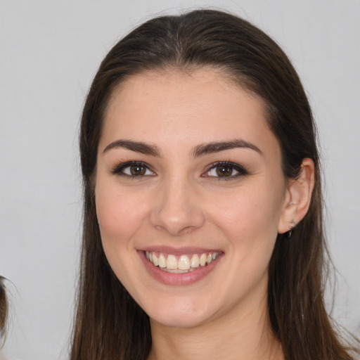 Joyful white young-adult female with long  brown hair and brown eyes