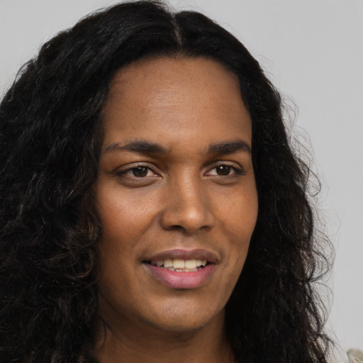 Joyful black young-adult female with long  brown hair and brown eyes