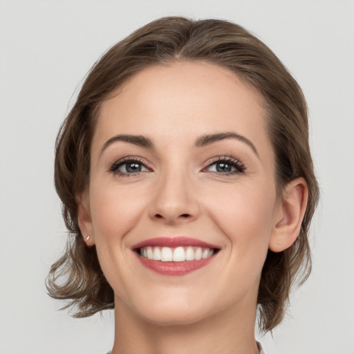 Joyful white young-adult female with medium  brown hair and grey eyes