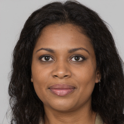 Joyful black young-adult female with long  brown hair and brown eyes