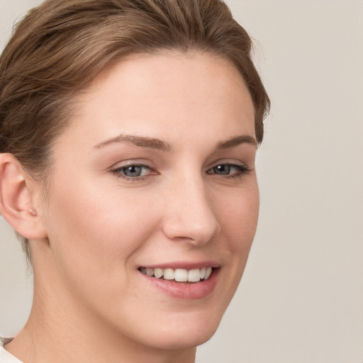 Joyful white young-adult female with short  brown hair and grey eyes