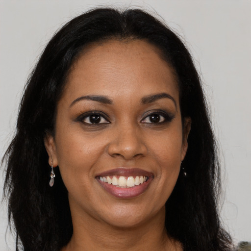 Joyful black young-adult female with long  brown hair and brown eyes