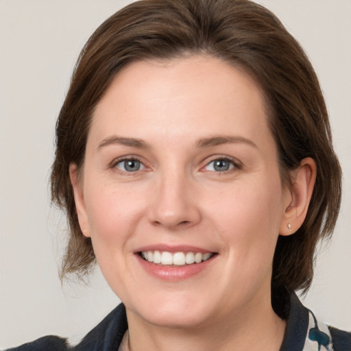 Joyful white young-adult female with medium  brown hair and grey eyes