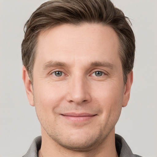 Joyful white young-adult male with short  brown hair and grey eyes