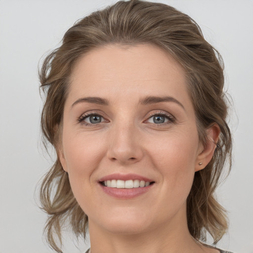 Joyful white young-adult female with medium  brown hair and grey eyes